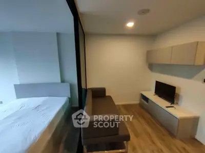 Modern studio apartment with cozy living area and bedroom separated by glass partition.