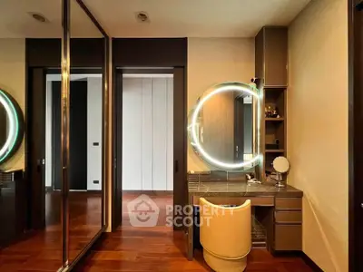 Luxurious bedroom with modern vanity and mirrored closet doors, featuring elegant wood flooring.