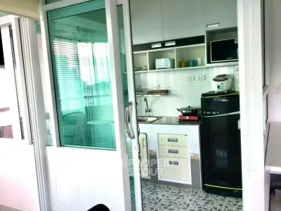 Compact kitchen with modern appliances and sliding glass door in cozy apartment.