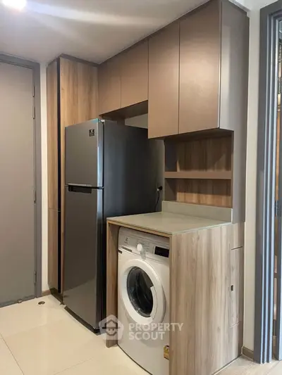Modern kitchen with sleek fridge and built-in washing machine in compact design.