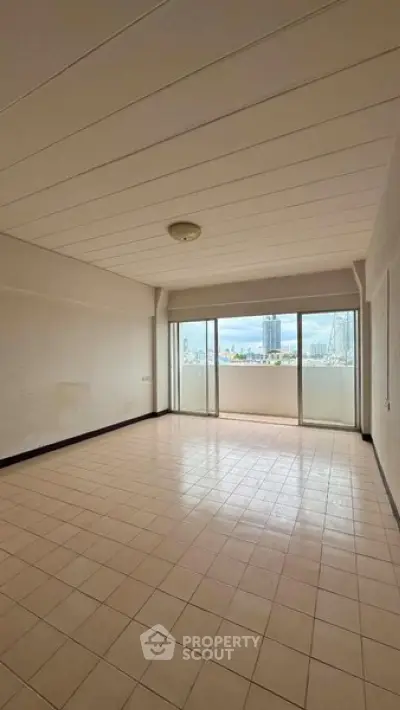 Spacious empty living room with large windows offering city skyline views.