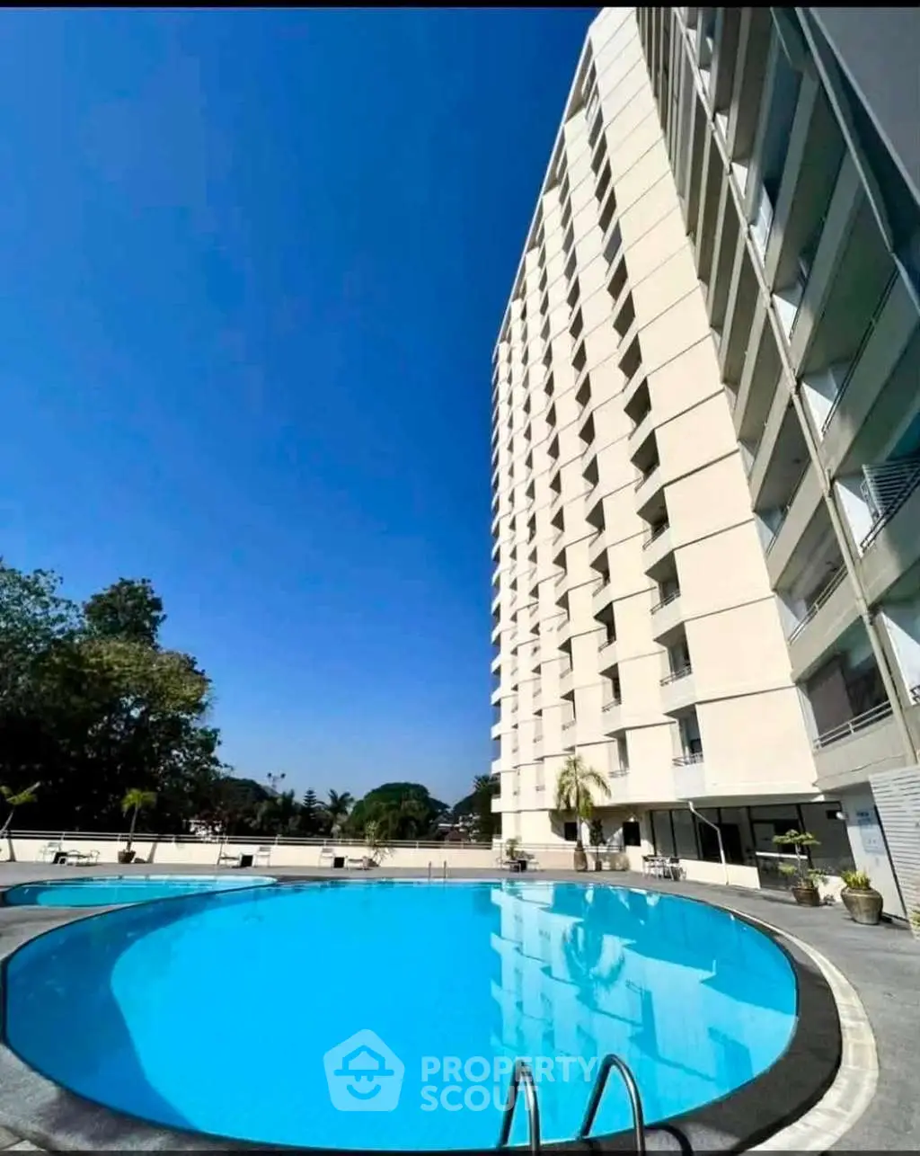 Luxurious high-rise building with a stunning pool and clear blue sky, perfect for modern living.