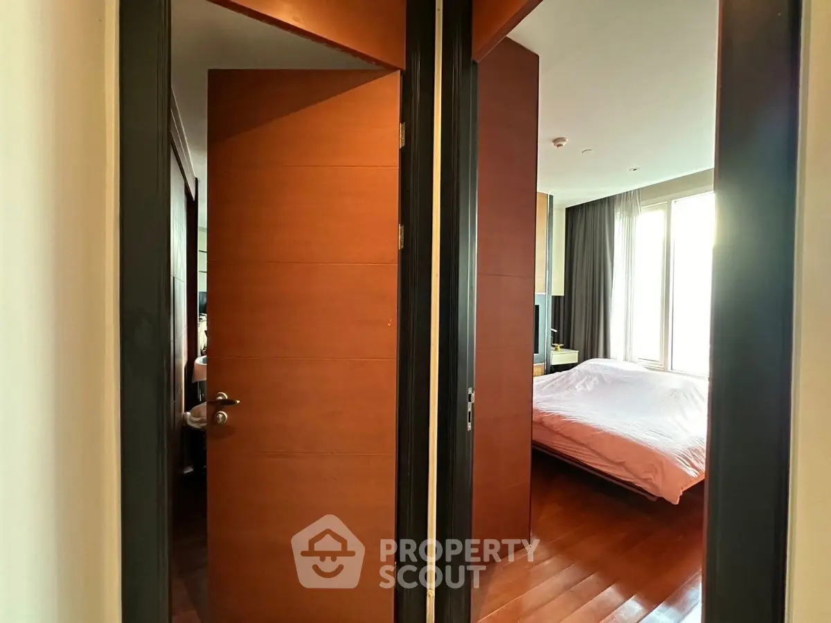 Spacious bedroom with wooden flooring and large windows for natural light