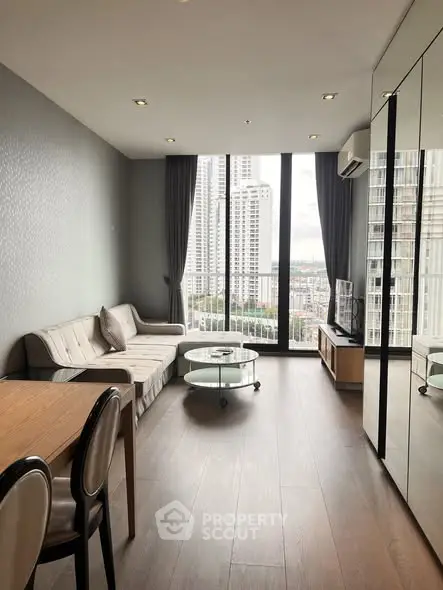 Modern living room with floor-to-ceiling windows and city view in high-rise apartment.