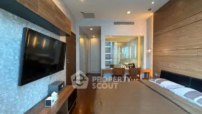 Luxurious modern bedroom with wood paneling and large TV, featuring a cozy workspace and elegant decor.