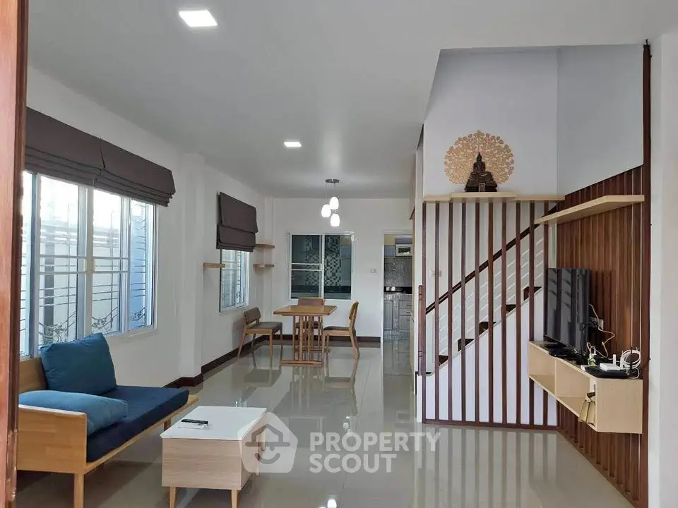 Modern living room with sleek furniture and open layout, featuring a stylish staircase and ample natural light.