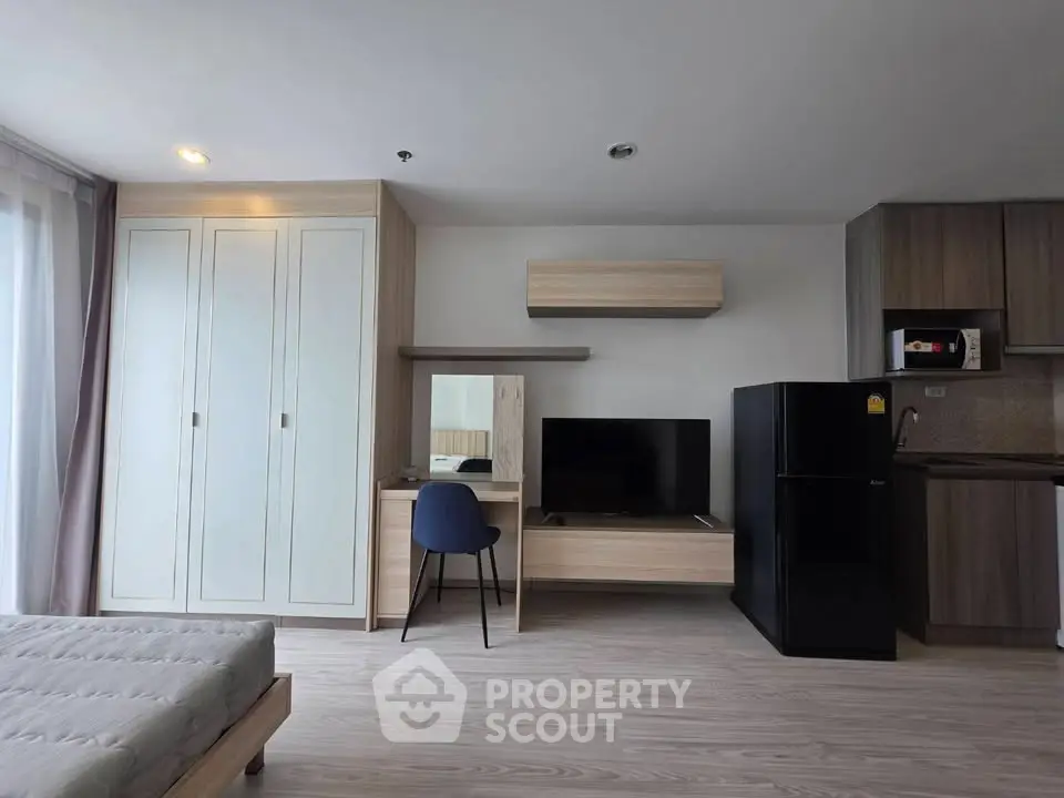 Modern studio apartment with sleek furniture and kitchen appliances, featuring a cozy living space and ample storage.
