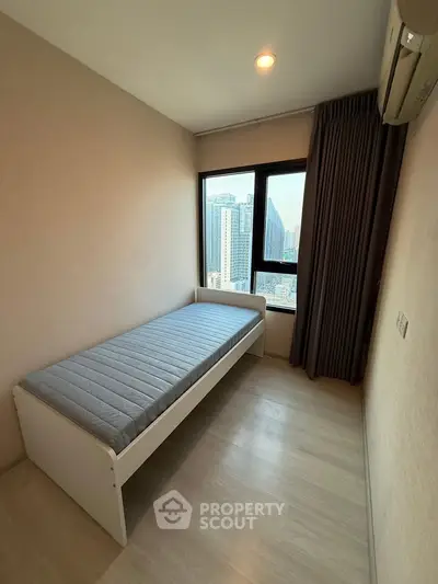 Cozy bedroom with city view, featuring a single bed and large window, perfect for urban living.