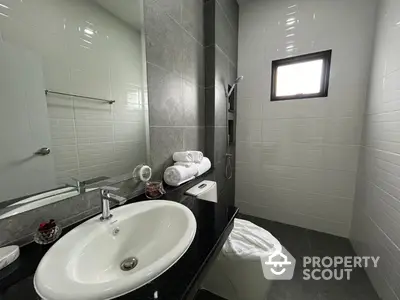 Modern bathroom with sleek design featuring a large mirror, elegant sink, and stylish tiles.