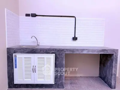 Modern minimalist kitchen with sleek concrete countertop and white tile backsplash