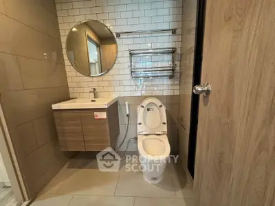 Modern bathroom with sleek fixtures and round mirror in a contemporary apartment.
