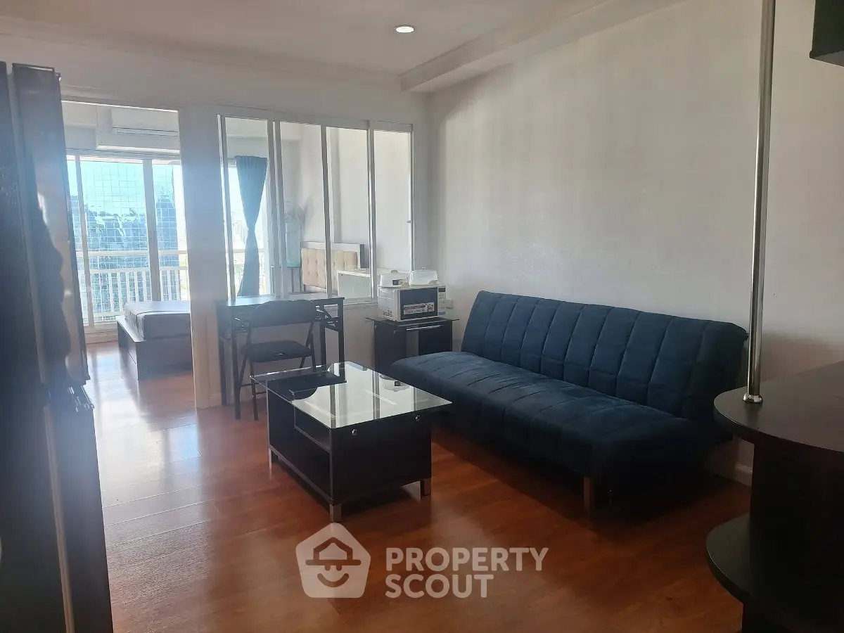 Modern living room with sleek furniture and wooden flooring, featuring a cozy sofa and glass coffee table.