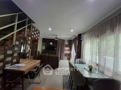 Spacious modern living room with dining area and staircase, featuring large windows and stylish decor.