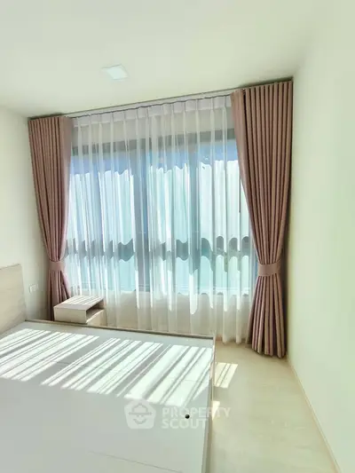 Bright bedroom with large window and elegant curtains, perfect for natural light lovers.