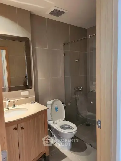 Modern bathroom with glass shower and wooden vanity in a sleek apartment.