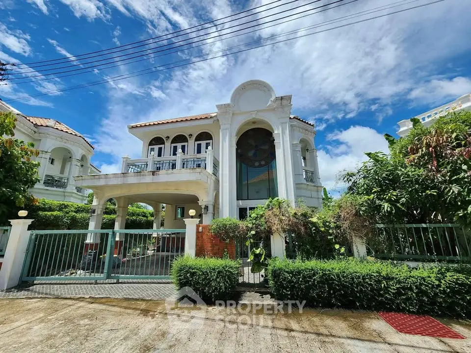 Stunning two-story villa with lush greenery and elegant architecture under a bright blue sky.