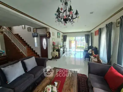 Elegant living room with chandelier and stylish decor, featuring large windows and a cozy seating area.