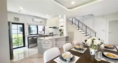 Modern open-layout kitchen and dining area with elegant staircase and natural light.