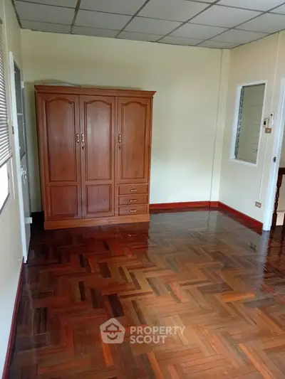 Spacious room with wooden wardrobe and parquet flooring, ideal for customization.