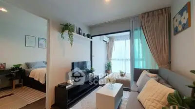 Modern living room with cozy decor and natural light, featuring a sleek TV unit and comfortable seating.