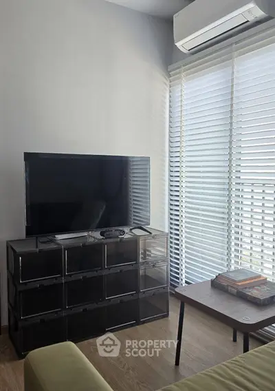 Modern living room with sleek TV setup and natural light from large windows.