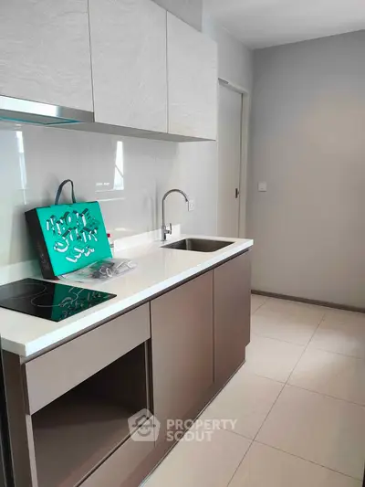 Modern kitchen with sleek cabinetry and electric cooktop in contemporary apartment.