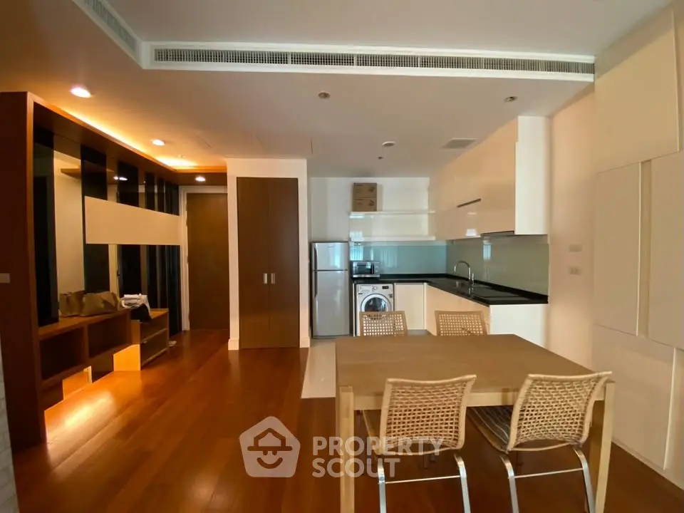 Modern open-plan kitchen and dining area with wooden flooring and sleek design.