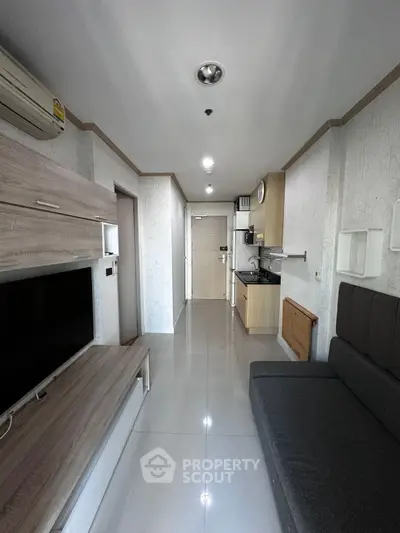 Modern apartment interior with sleek kitchen and cozy living area, featuring stylish furniture and efficient layout.