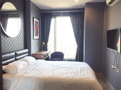 Stylish bedroom with modern decor, large window, and wall-mounted TV in a cozy apartment.