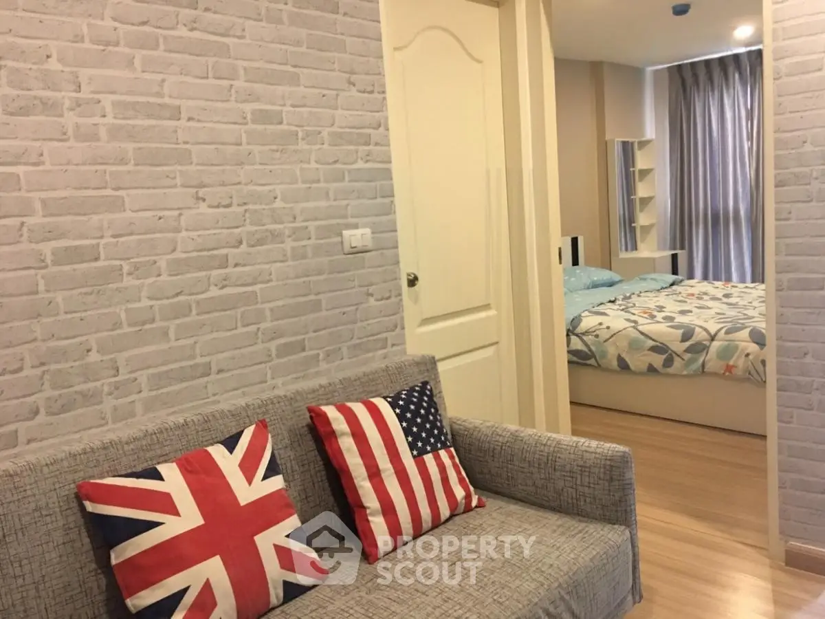 Cozy living room with stylish brick wall and view into a modern bedroom, perfect for urban living.