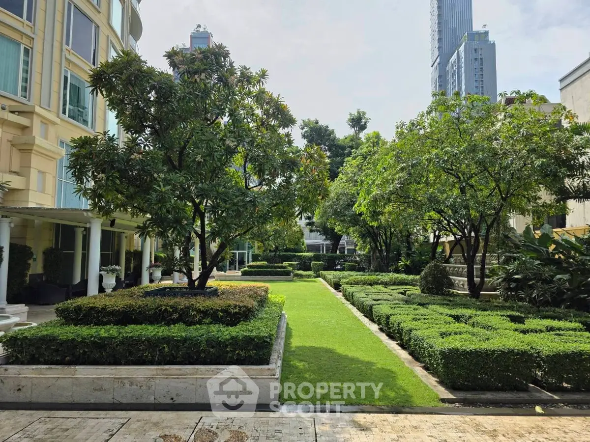 Luxurious garden view with manicured hedges and towering buildings in the background