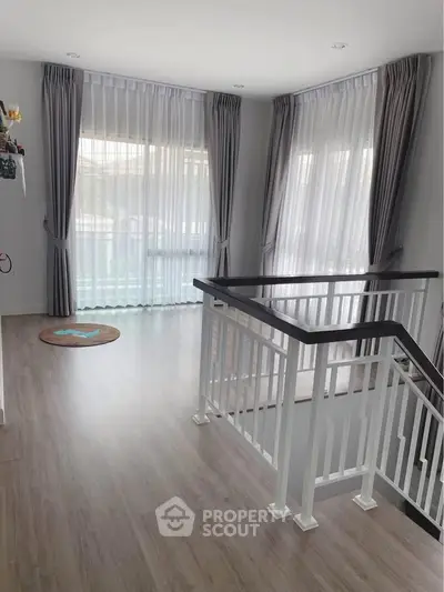 Bright and airy interior with large windows and elegant curtains, showcasing modern flooring and stylish railing.