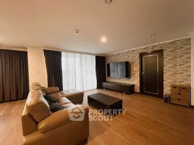 Spacious modern living room with leather sofa and wall-mounted TV, featuring elegant wood flooring and stylish decor.