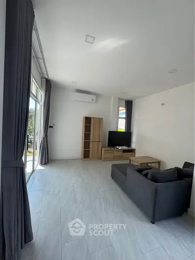 Spacious modern living room with large windows and sleek furniture, perfect for relaxation and entertainment.