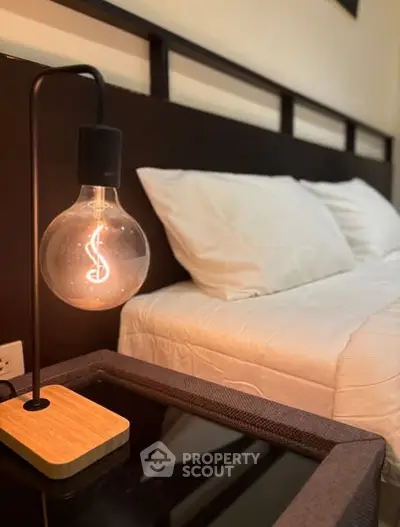 Cozy bedroom with modern lamp and plush bedding for ultimate relaxation.