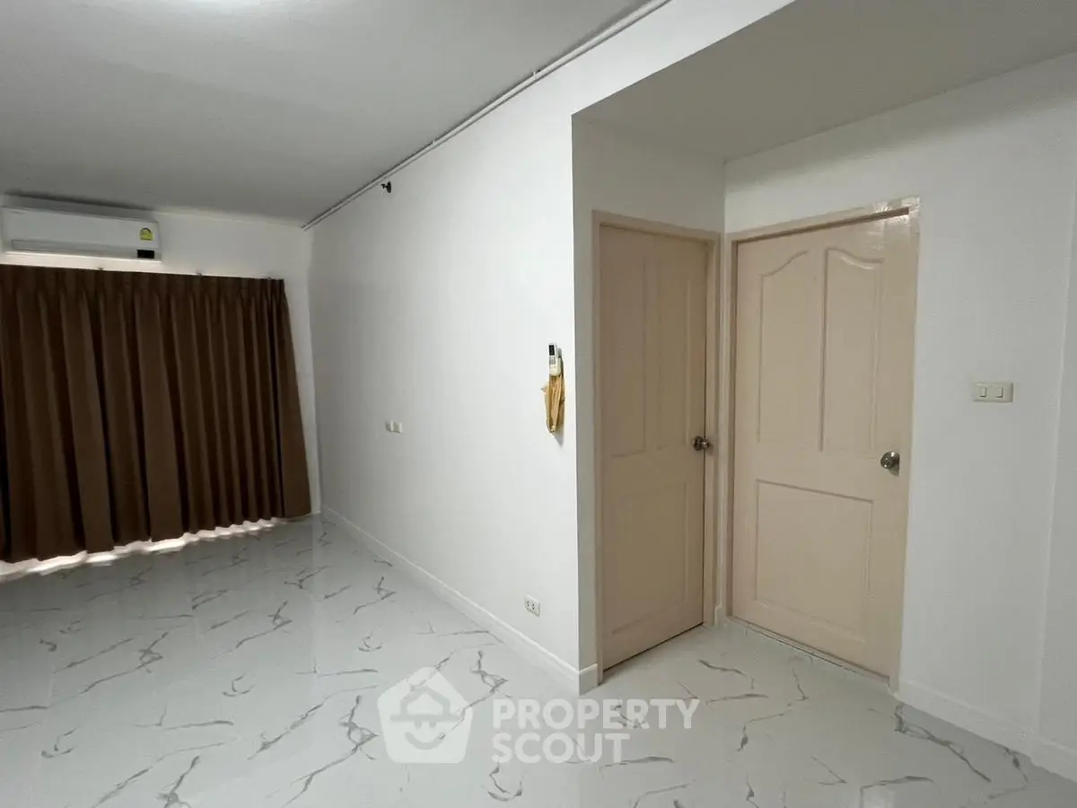 Spacious room with marble floor and brown curtains, ideal for versatile use.