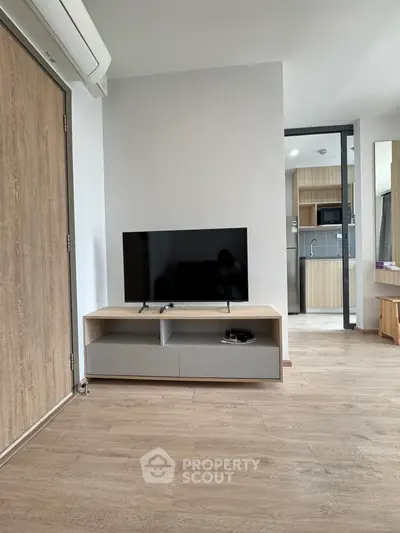 Modern living room with sleek TV stand and open kitchen view, showcasing contemporary interior design.