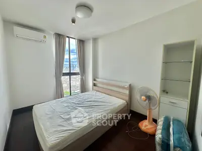 Spacious bedroom with city view, featuring modern furnishings and natural light.