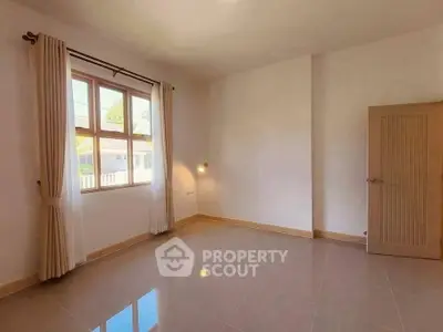 Spacious empty room with large window and neutral decor, perfect for customization.