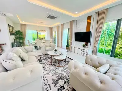 Luxurious living room with elegant decor and large windows offering lush garden views.