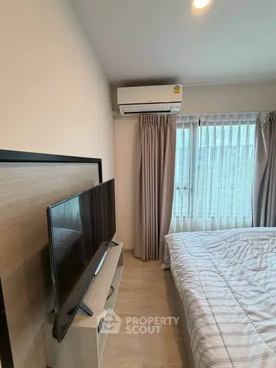 Cozy bedroom with modern TV setup and air conditioning, perfect for relaxation.