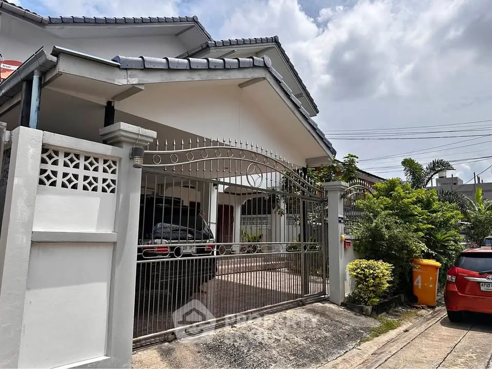 Charming suburban house with gated driveway and lush greenery, perfect for family living.