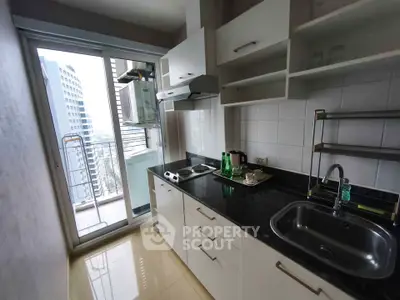 Modern kitchen with sleek black countertops and balcony view in urban apartment