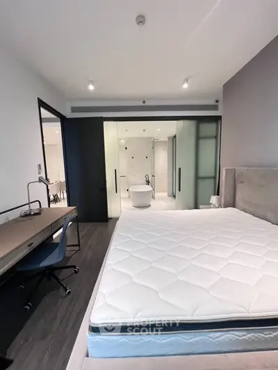 Modern bedroom with ensuite bathroom featuring a freestanding bathtub and sleek design.