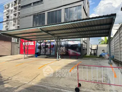 Modern commercial building with covered parking area and vibrant signage.