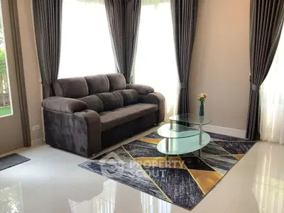 Stylish living room with modern sofa, elegant curtains, and chic glass coffee table on geometric rug.