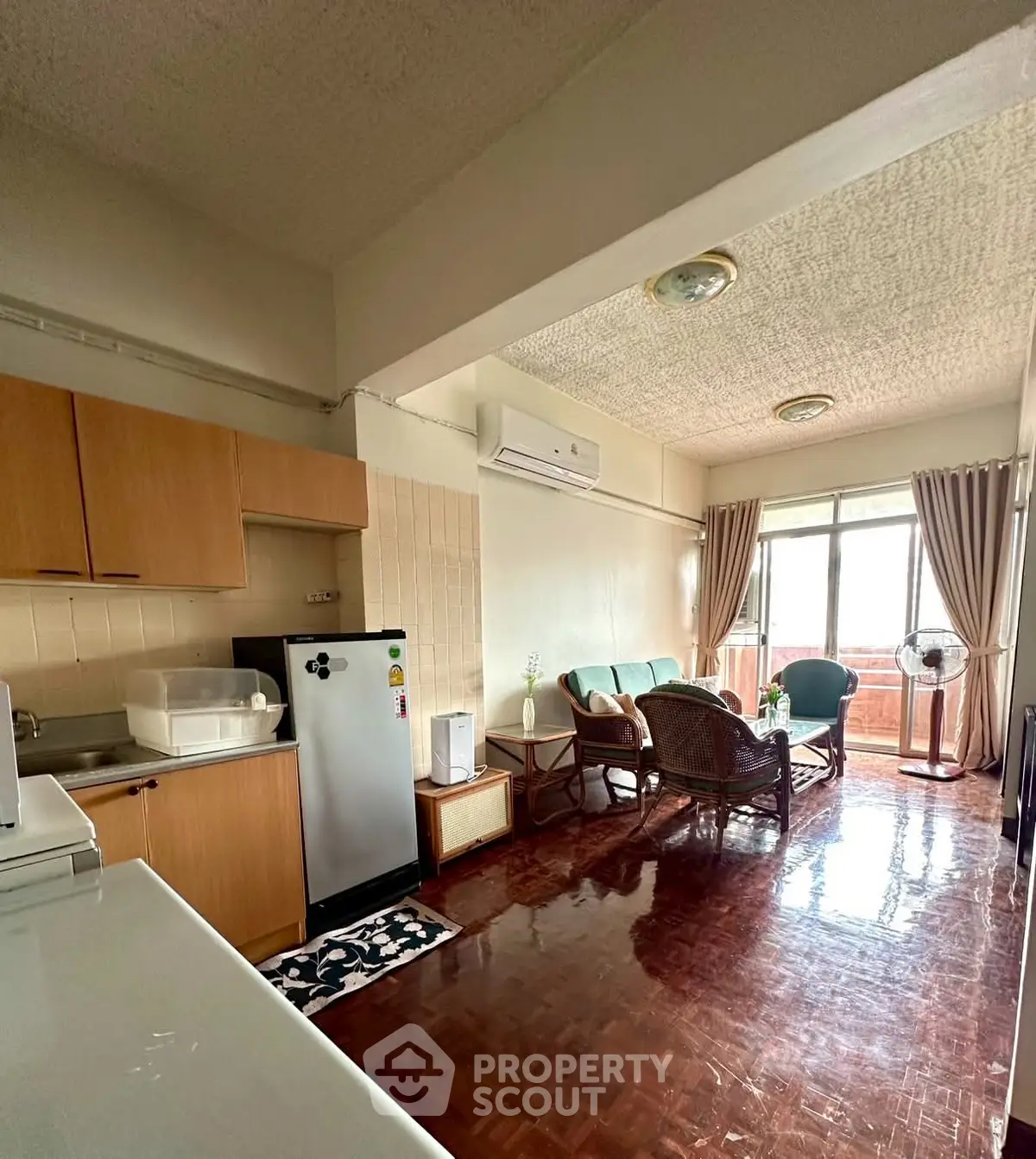 Charming living room with wooden flooring and cozy seating area, featuring natural light and modern appliances.