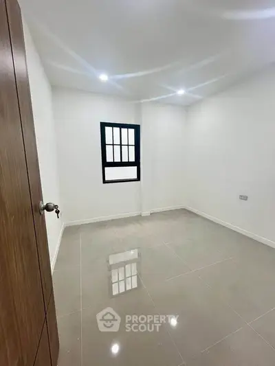 Spacious empty room with glossy tiled floor and modern window, perfect for customization.