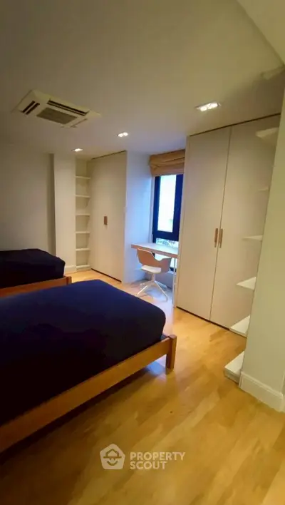 Modern bedroom with twin beds, built-in wardrobes, and a study nook.