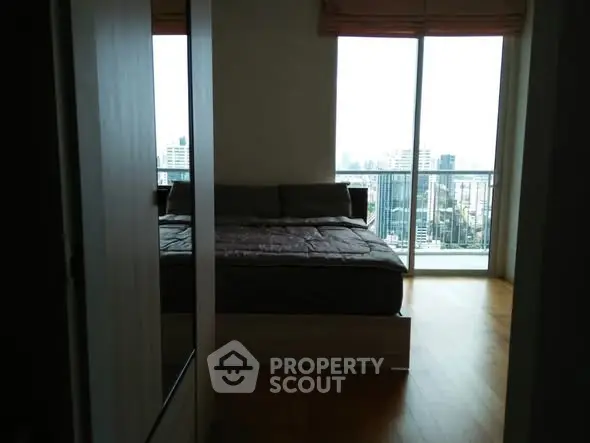 Modern bedroom with city view and large window in high-rise apartment